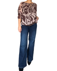 Blouse brune pour femme avec imprimé de formes irrégulières avec jean évasé et bottillons noirs.