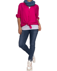 Jeans skinny pour femme avec brillants dans le bas avec chemise fuchsia et foulard.
