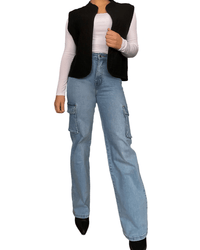 Veste noire sans manches style rembourré pour femme avec jeans cargo et bottillons noirs.