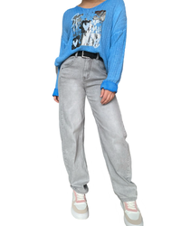 Jeans baggy gris pour femme avec ceinture et chandail bleu.