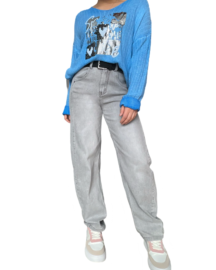 Jeans baggy gris pour femme avec ceinture et chandail bleu.