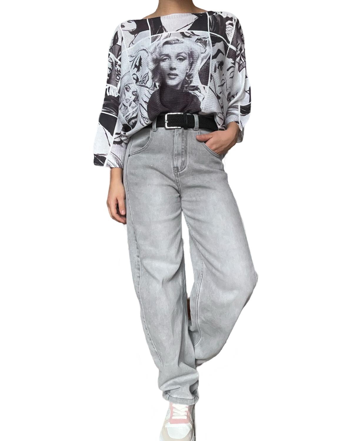 Jeans baggy gris pour femme avec chandail en mailles et ceinture noire.