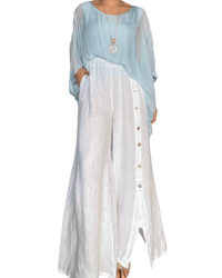 Pantalon palazzo blanc avec boutons sur le côté pour femme avec blouse et collier.