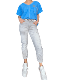 T-shirt bleu électrique avec patchwork pour femme avec ceinture argentée et sneakers.