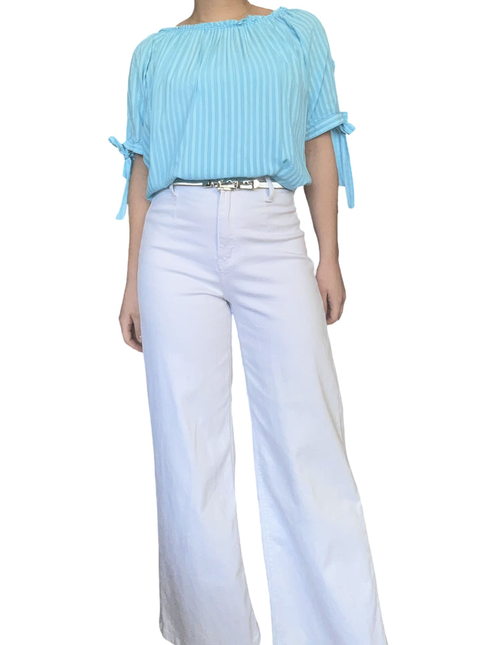 Blouse rayée dans des tons de bleu pour femme avec pantalon blanc.