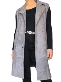Veste trench gris sans manche pour femme avec ceinture et chandail noir.