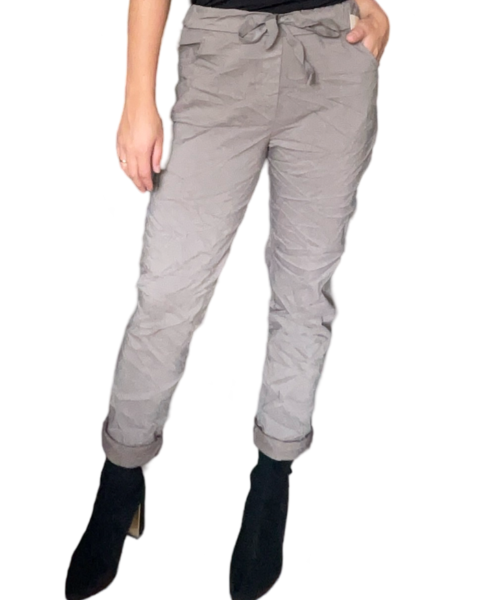 Pantalon beige foncé à taille élastique avec cordon pour femme avec bottillons noirs.