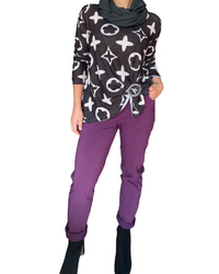 Chandail noir pour femme avec imprimé de fleur de monogramme avec pantalon mauve et bottillons.