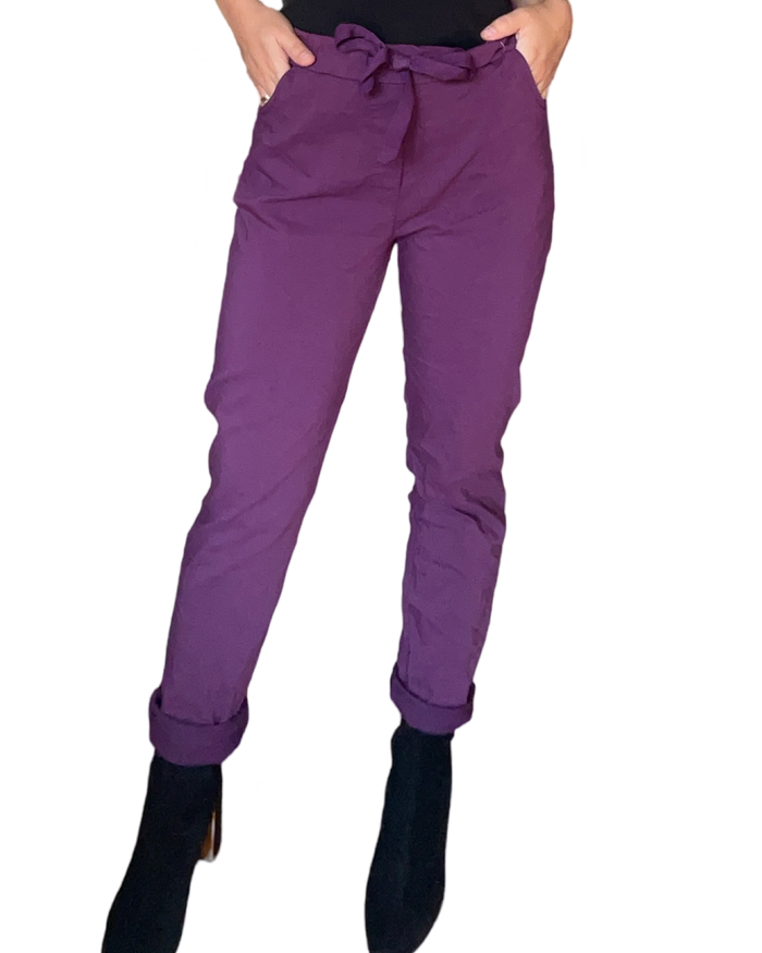 Pantalon mauve à taille élastique avec cordon pour femme avec bottillons noirs.