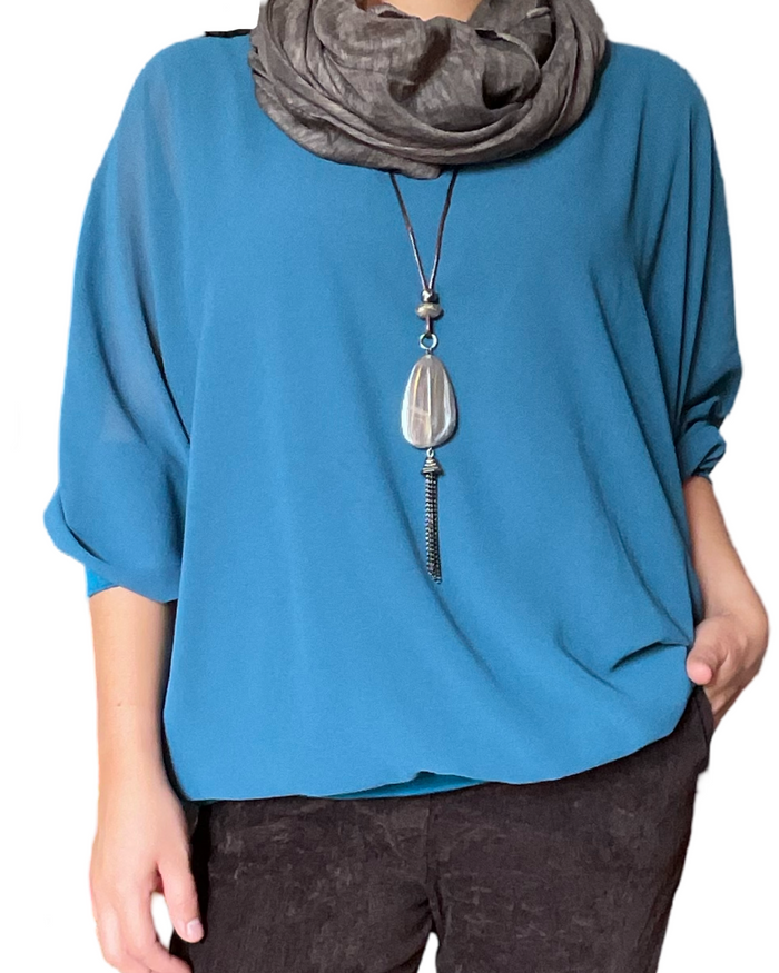 Blouse bleue à manches longues pour femme avec collier long.