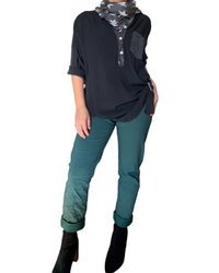 Pantalon vert forêt à taille élastique avec cordon pour femme avec blouse noire, foulard et bottillons.