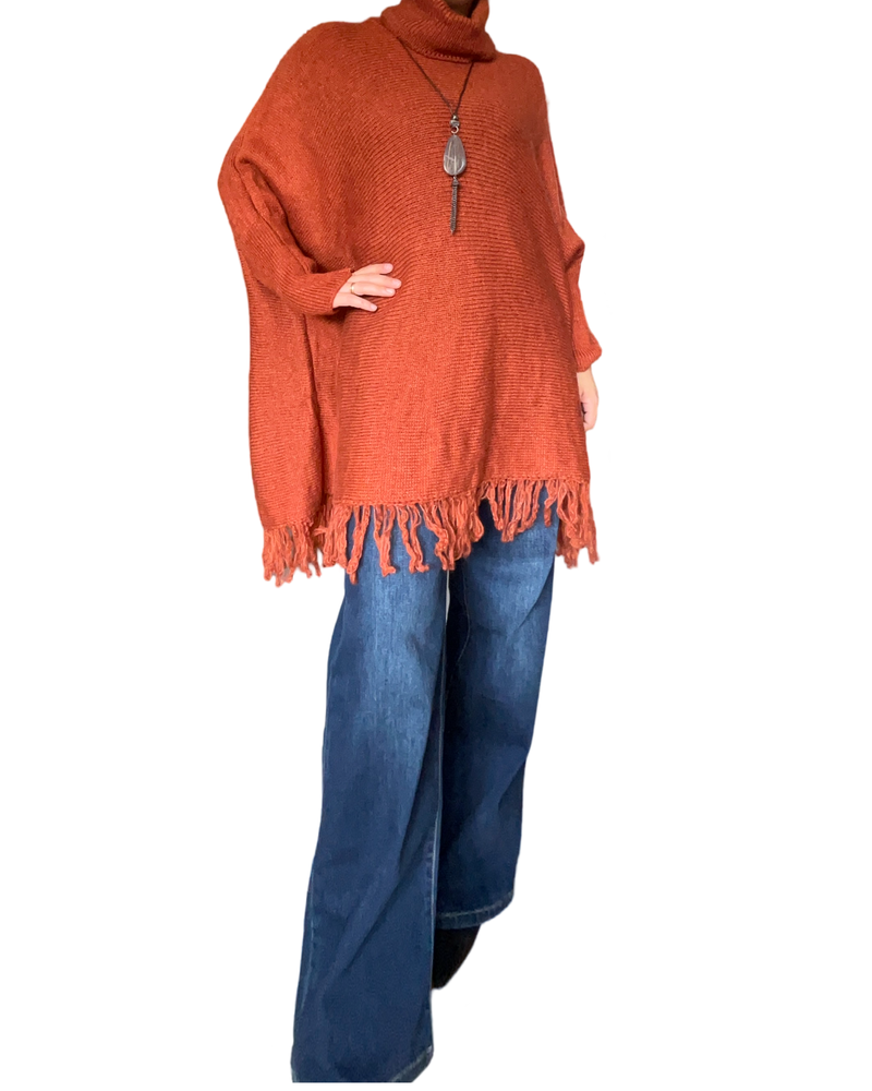 Chandail orange rouille long à col roulé pour femme avec collier long et jean évasé.