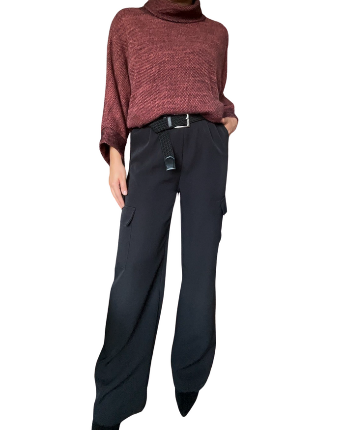 Chandail rouge à manches longues et col roulé pour femme avec pantalon noir cargo et bottillons.