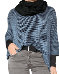 Chandail bleu jeans en maille pour femme avec foulard noir et ceinture tressée noire.