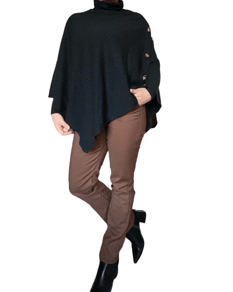 Chandail noir style poncho pour femme avec pantalon brun et bottillons noirs. 