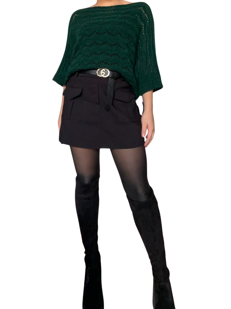 Jupe courte noire cargo avec ceinture noire pour femme avec chandail vert.