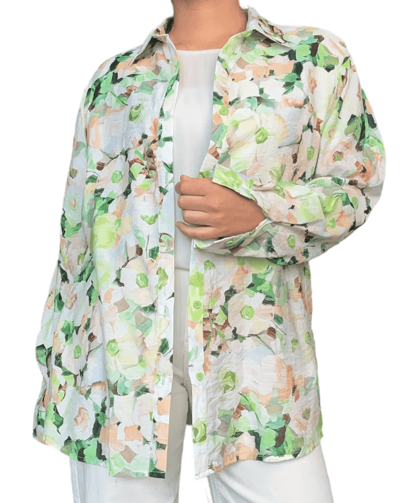 Chemise avec imprimé floral vert et beige pour femme avec chandail blanc en dessous. 