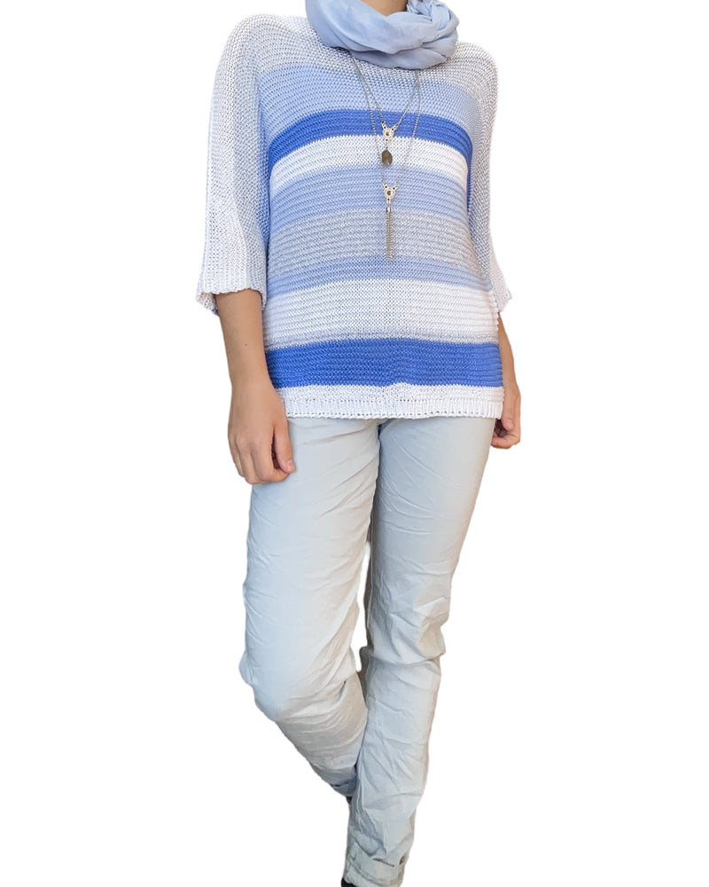 Chandail blanc en mailles rayé bleu et gris pour femme avec collier long et sneakers.