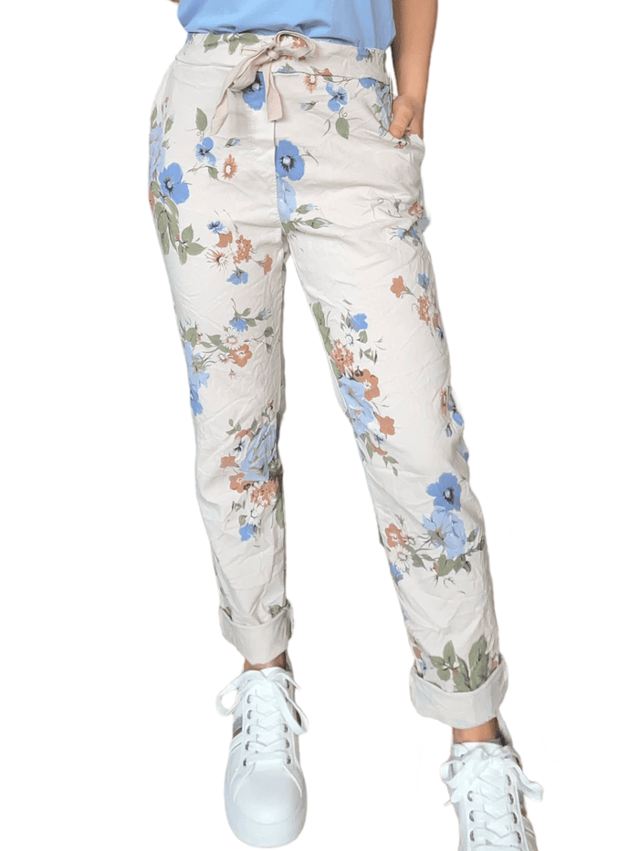 Pantalon beige à taille élastique avec imprimé floral pour femme avec sneakers.