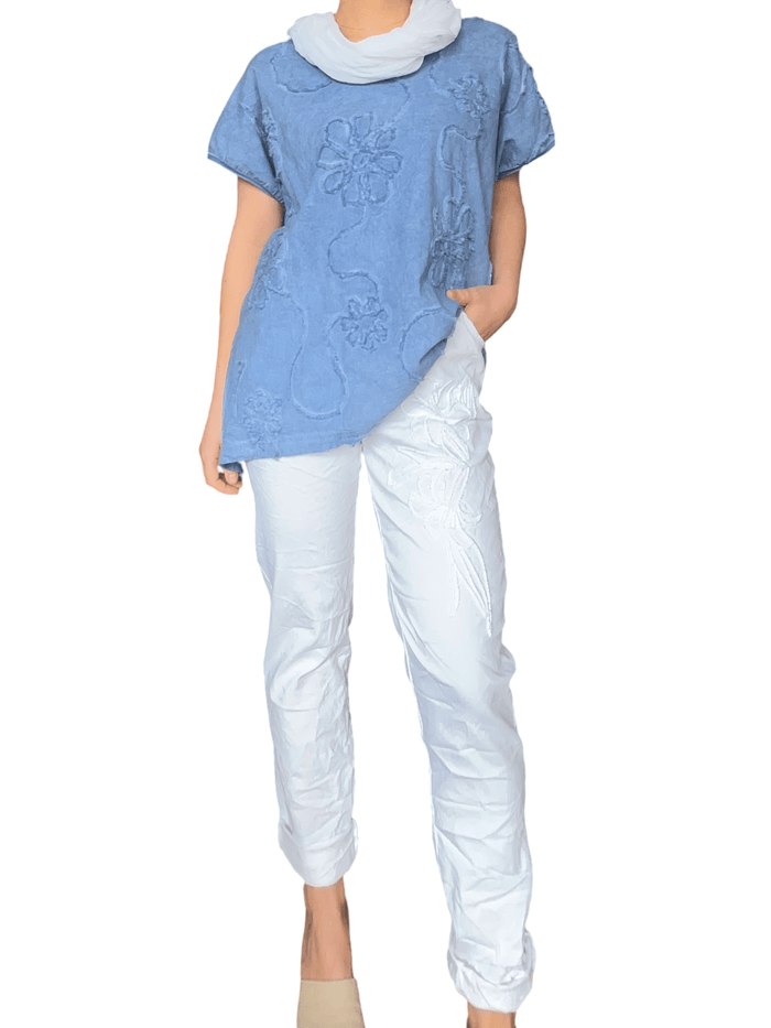 T-shirt bleu jean à motifs floraux monochromes pour femme avec pantalon blanc.
