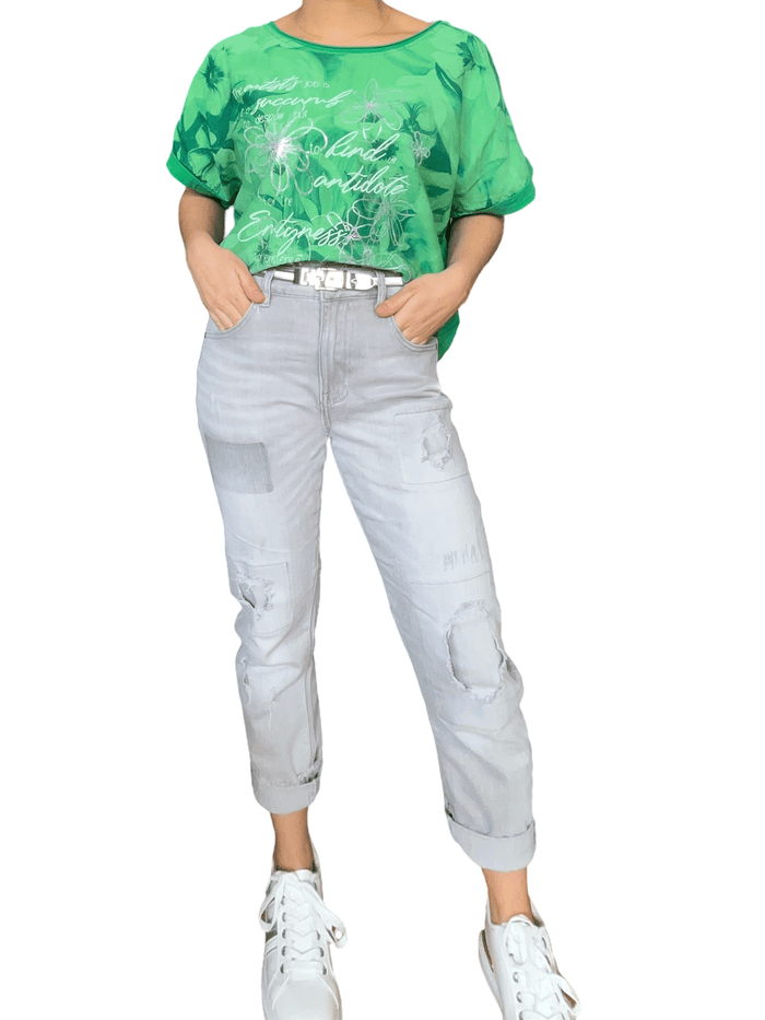 T-shirt vert avec imprimé floral argenté et vert pour femme avec jeans et sneakers.