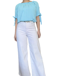 Blouse rayée dans des tons de bleu pour femme avec pantalon blanc.