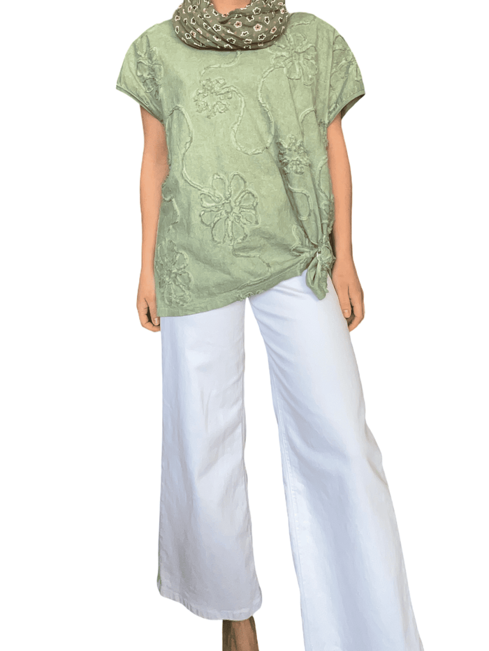 T-shirt vert à motifs floraux brodés pour femme avec pantalon blanc.