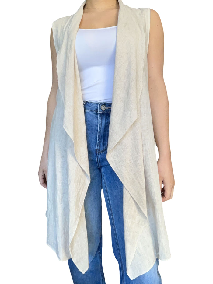 cardigan long beige sans manches pour femme avec camisole blanche.