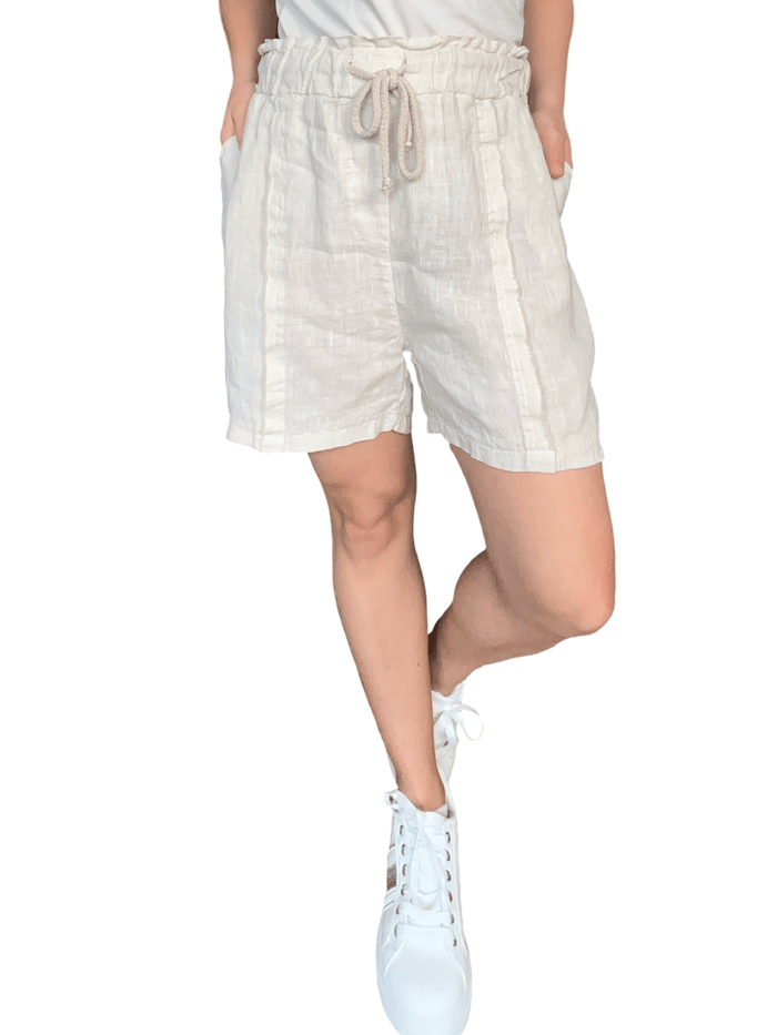 Short beige en lin à taille élastique avec cordon pour femme avec sneakers.