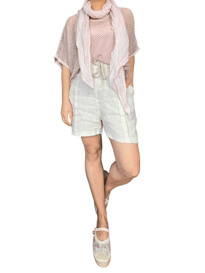 Chandail rose pâle en mailles pour femme avec short et souliers.