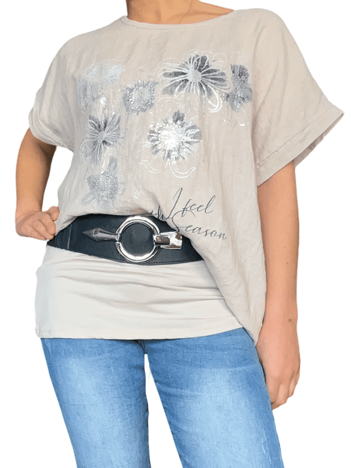 T-shirt beige pour femme avec imprimé floral argenté et blanc avec camisole beige en dessous et ceinture.