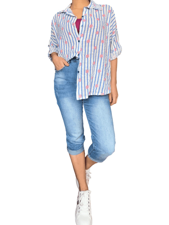 Chemise blanche rayée bleue à motifs floraux pour femme avec capri et sneakers.