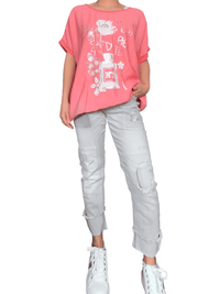 T-shirt corail avec imprimé floral blanc pour femme avec sneakers.