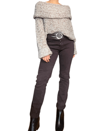 Chandail beige en crochet à col asymétrique pour femme avec jeans et bottillons.