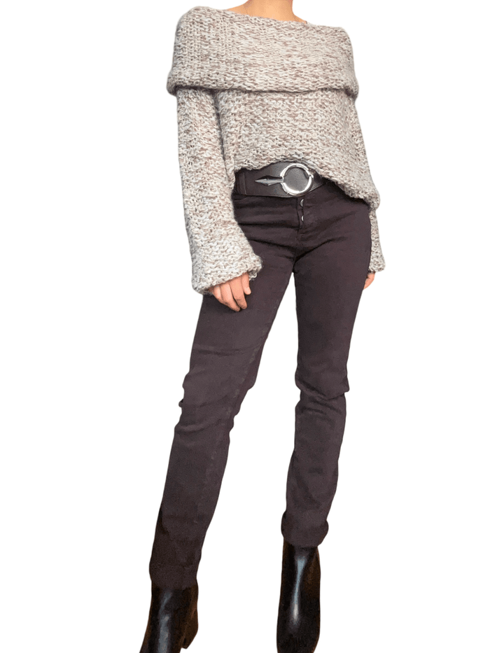 Chandail beige en crochet à col asymétrique pour femme avec jeans et bottillons.