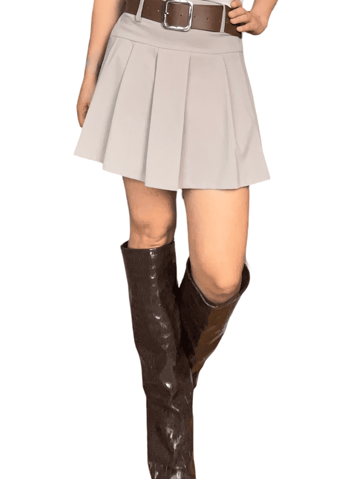 Jupe plissée beige avec ceinture pour femme avec bottes.
