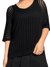 Chandail noir mince en mailles pour femme avec camisole noire en dessous.
