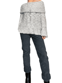 Chandail gris et blanc en crochet à col asymétrique pour femme avec pantalon et bottillons.