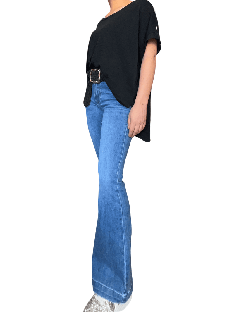 Jeans flare bleu clair pour femme avec ceinture et sneakers.