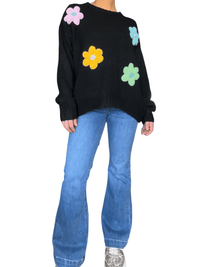 Chandail noir à manche longue à motifs floraux pour femme avec jeans et sneakers.