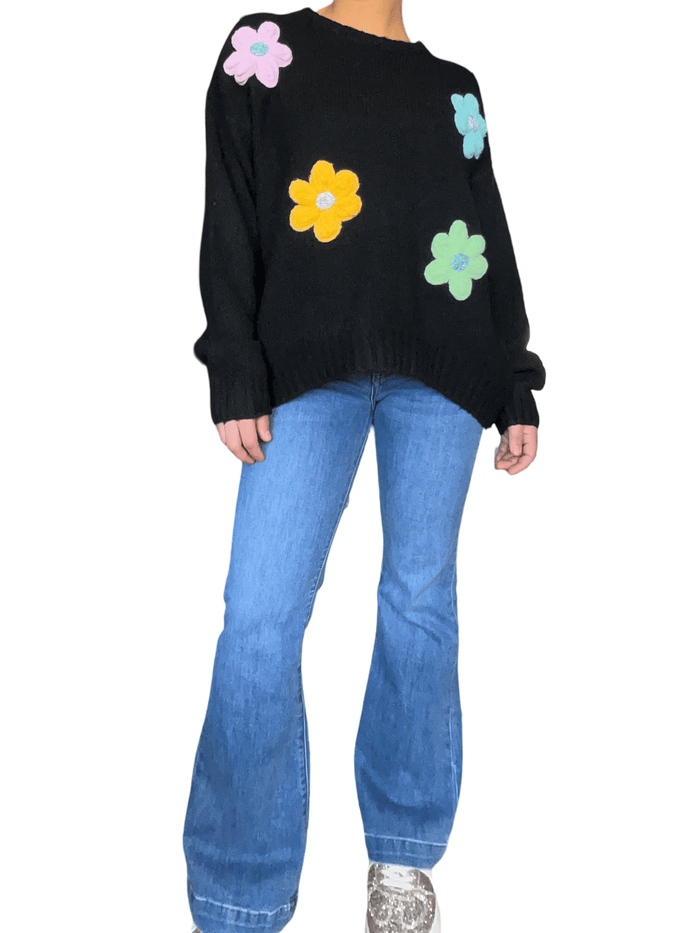 Chandail noir à manche longue à motifs floraux pour femme avec jeans et sneakers.