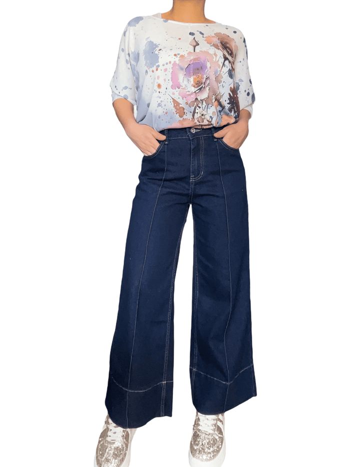 Chandail blanc crème avec imprimé abstrait et fleurs pour femme avec jean évasé et sneakers.