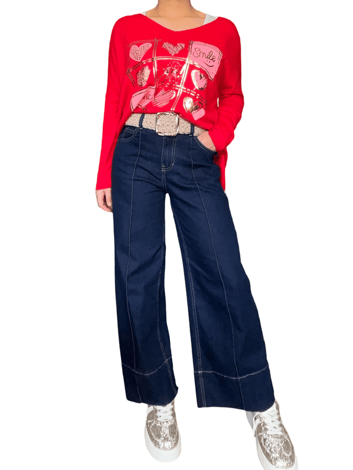 Chandail rouge avec imprimé de cœurs pour femme avec jeans et sneakers.