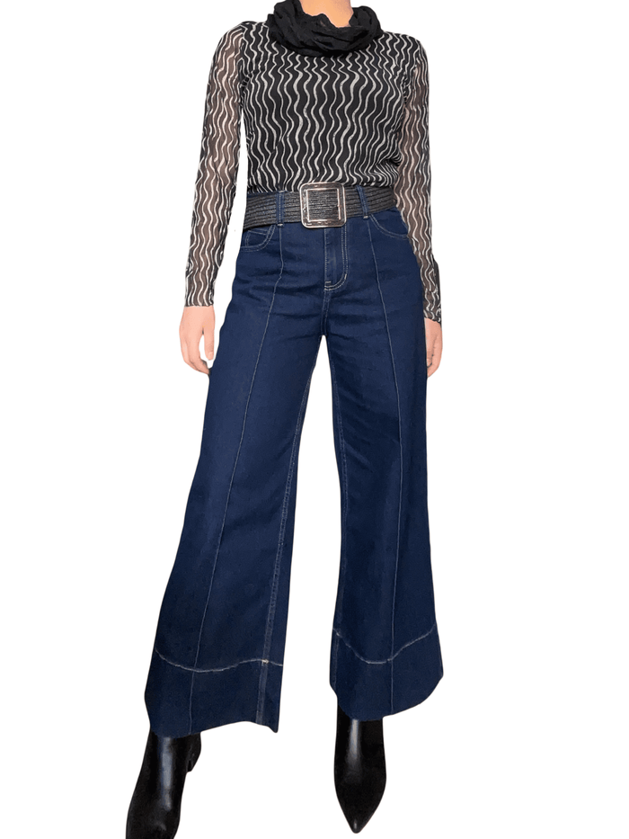 Chandail en mailles noir et beige pour femme avec jeans et bottillons.
