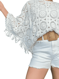 Chandail blanc en crochet à motifs bohèmes pour femme avec short.