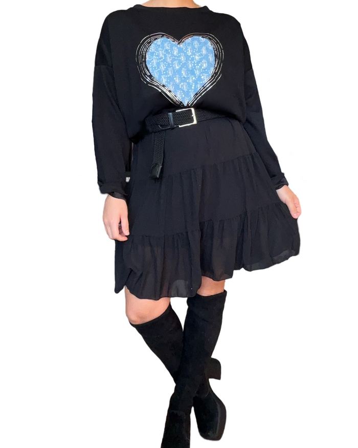 Chandail noir pour femme avec un cœur texturé bleu avec ceinture noire et jupe noire.